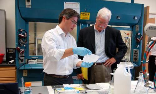 Scientist giving demonstration to legislator in lab.